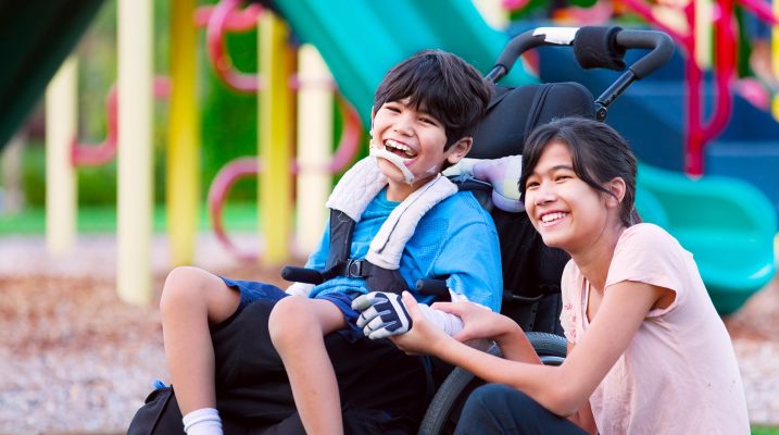 Disabled brother in wheelchair sitting with sister