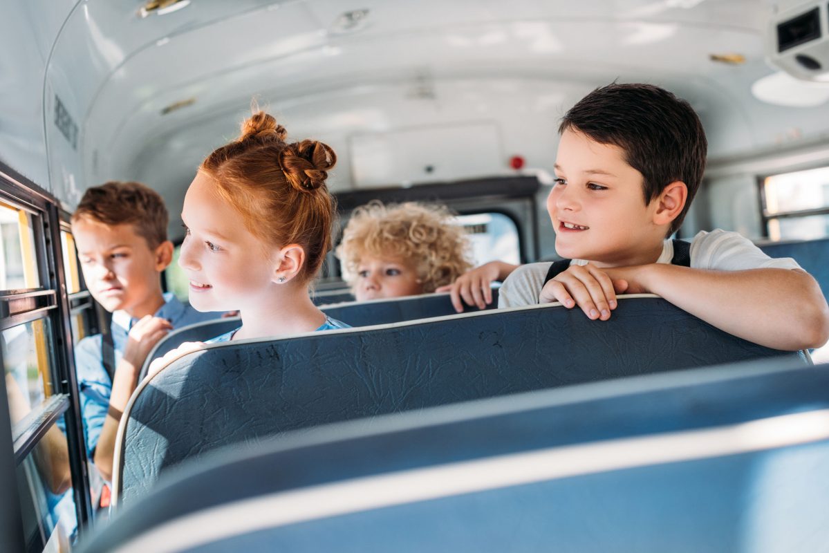 group of pupils riding on school bus and looking through window