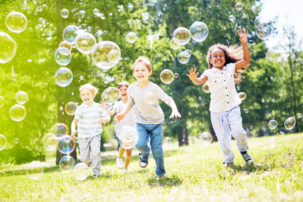 Children in a park chasing after bubbles